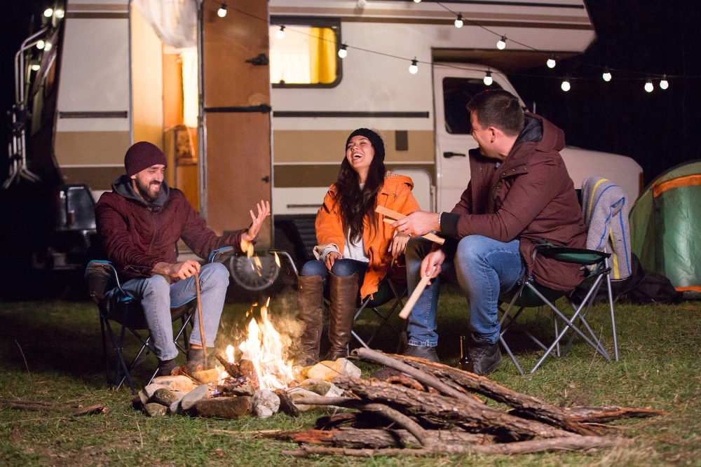 Group of friends gathered around a warm campfire under a starry night sky