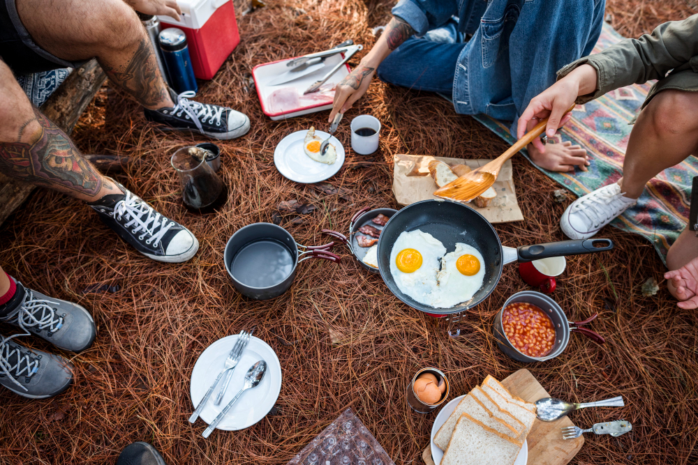 Campers preparing a meal on a portable stove with a beautiful mountain backdrop